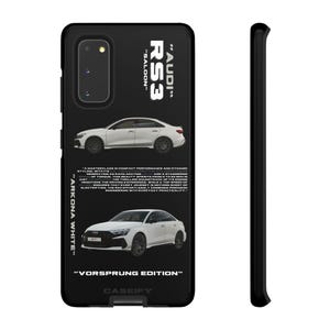 May include: Black phone case with two white Audi RS3 cars. The case displays the text "AUDI", "RS3", "SALOON", "ARKONA WHITE", and "VORSPRUNG EDITION". The case is designed for a Samsung Galaxy S20.