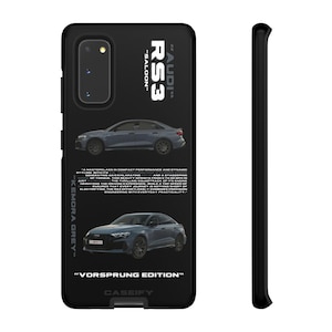 May include: Black phone case with two grey Audi RS3 car illustrations. The case has the text "RS3", "AUDI", "SALOON", "KEMORA GREY", and "VORSPRUNG EDITION". The case is designed for a Samsung phone.