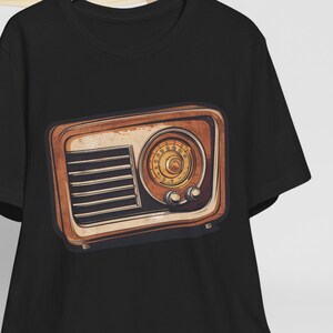 Könnte beinhalten: Schwarzes T-Shirt mit einem Vintage-Radio-Motiv. Das Radio ist braun mit einem goldenen Zifferblatt und Knöpfen.