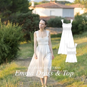 Op de afbeelding: Een witte, mouwloze jurk en top met een gerimpelde halslijn en bandjes. De jurk is midi-lang en de top is kort. Het model draagt de jurk en loopt op een pad in een grasveld.