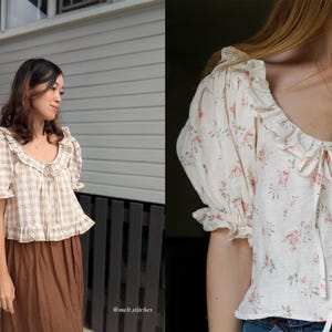 Pode incluir: Duas blusas s&atilde;o mostradas. Uma &eacute; um padr&atilde;o xadrez bege e branco com bordas com babados e mangas curtas. A outra &eacute; uma blusa creme com estampa floral, decote com babados e mangas curtas bufantes. Ambas t&ecirc;m um detalhe de la&ccedil;o no decote.