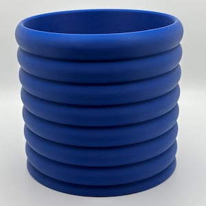 May include: A blue ceramic planter with a ribbed design. The planter is cylindrical and has a smooth, matte finish.
