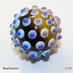 May include: A black glass sphere with a textured surface, covered in small blue, white, and purple circles. The sphere is 1 1/2 inches in diameter.
