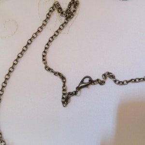 May include: A close-up of a bronze chain necklace with a lobster clasp.