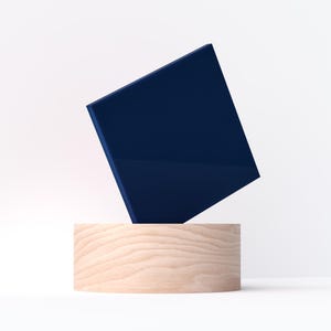 May include: A navy blue square object is balanced above a light wood cylinder. The square has a glossy finish, and the wood grain is visible on the cylinder. The background is plain white.