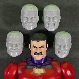 May include: A red and purple action figure with a black mustache and five interchangeable gray heads. The figure has a muscular build and is wearing a red suit with purple accents. The heads display various expressions.