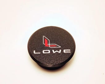 May include: Black round sticker with a white "LOWE" text and a red and white logo.