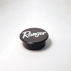 May include: Black round bottle stopper with the word "Ranger" in white lettering.