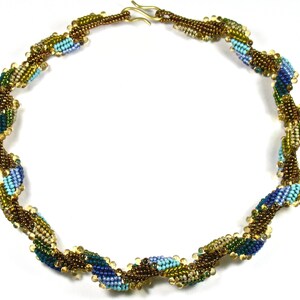 May include: A beaded necklace with a spiral design. The necklace features a mix of blue, teal, green, and gold beads. The beads are strung together to create a twisted rope effect. The clasp is gold-colored.
