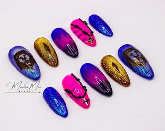 Puede incluir: Un conjunto de diez uñas artificiales con varios diseños. Las uñas presentan una mezcla de colores, incluyendo azul, dorado, rosa y morado. Algunas uñas tienen un efecto degradado, mientras que otras tienen un diseño de calavera. Algunas uñas tienen una cadena de cuentas.