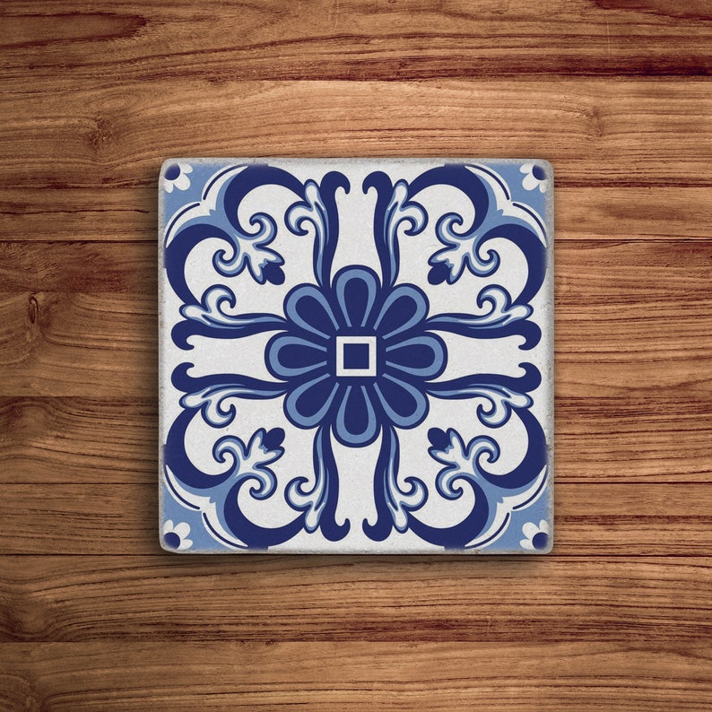May include: A blue and white ceramic tile with a floral design. The tile has a white background with a blue floral pattern in the center and around the edges.