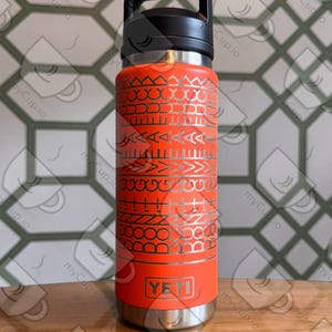 Könnte beinhalten: Eine orangefarbene YETI-Trinkflasche mit schwarzem Griff und Deckel. Die Flasche hat ein silbernes geometrisches Muster und das YETI-Logo. Die Edelstahlflasche ist so konzipiert, dass Getränke kalt oder heiß gehalten werden.