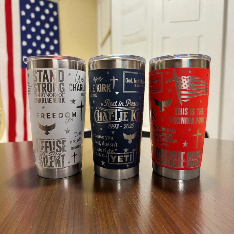Puede incluir: Tres vasos aislados de acero inoxidable con varios dise&ntilde;os patri&oacute;ticos. Uno es blanco con texto, una cruz y un &aacute;guila. El segundo es azul marino con texto y una cruz. El tercero es rojo con un dise&ntilde;o de bandera estadounidense y texto.