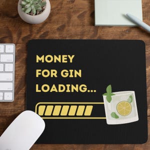 May include: Black mouse pad with the text "MONEY FOR GIN LOADING..." and a progress bar. A glass of gin with a lime wedge and a sprig of mint is on the right side of the progress bar.
