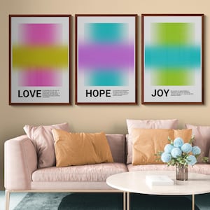 May include: Three framed art prints with abstract colour gradients. The prints read "LOVE," "HOPE," and "JOY" in bold white text. Each print has a different colour scheme: pink and yellow, teal and purple, and green and teal.
