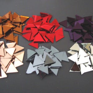 May include: Assortment of triangular mirror tiles in six colours: gold, red, purple, silver, grey, and clear. The tiles are approximately 2.5 cm in size.