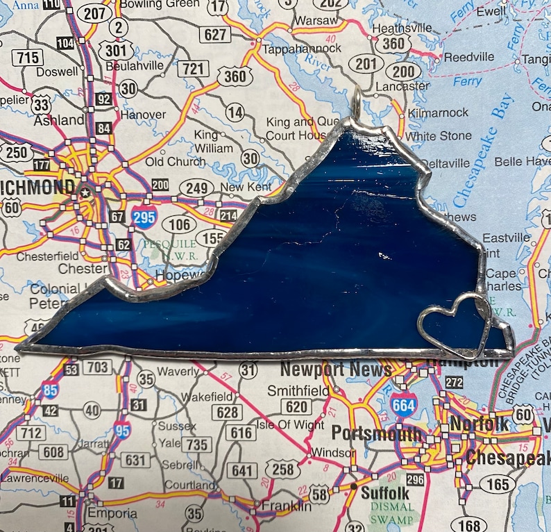 May include: A stained glass depiction of the state of Virginia, outlined in silver, with a heart-shaped cutout at the bottom. The glass is a deep blue color.