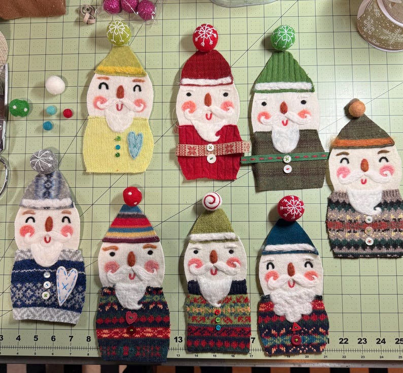 May include: Eight felt ornaments shaped like snowmen with different coloured hats and sweaters. The ornaments are decorated with white felt beards, buttons, and embroidered details.