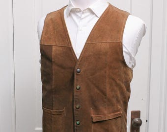 May include: A brown suede waistcoat with a V-neck, button fastening, and two front pockets. The waistcoat is displayed on a mannequin over a white collared shirt. The design is classic and tailored.