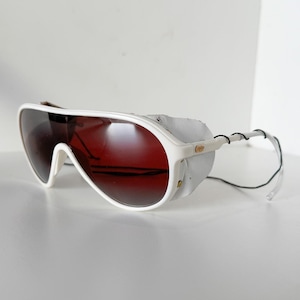 May include: White aviator sunglasses with a red tinted lens and a white leather strap. The sunglasses have a white frame and a black strap.