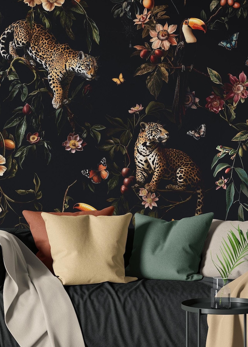 May include: A black and white wallpaper with a jungle theme. The wallpaper features two jaguars, a toucan, butterflies, and tropical plants. The wallpaper is displayed on a black couch with pillows.