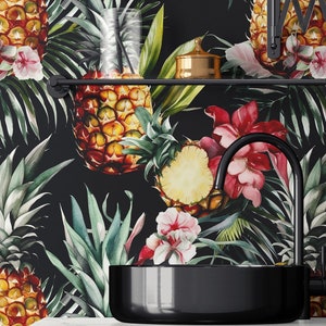 Puede incluir: Un tocador de baño negro con una encimera negra y un lavabo de porcelana negro. El salpicadero es un estampado tropical en blanco y negro con piñas, flores y hojas.