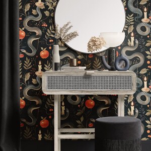May include: A vanity set with a round mirror, a light wood table with a woven front, and a matching stool with fringe. The wallpaper features a dark background with snakes, apples, and candles.