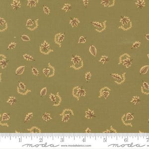May include: A sage green fabric featuring a repeating pattern of small, dark brown maple and oak leaves scattered across the surface. A white measuring tape is visible at the bottom edge, showing a length of 7 inches for the fabric width.
