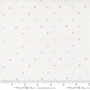 May include: A white fabric featuring a repeating pattern of small, multicolored cross-stitch symbols in yellow, pink, purple, and teal. A ruler at the bottom shows the fabric width spans over 7 inches, with the text moda www.modafabrics.com.