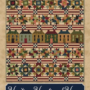 May include: A patchwork quilt with a cream background, featuring rows of colorful stars, houses, and geometric patterns in shades of red, blue, green, and tan. The quilt has a border of red stripes and the text "Heritage, Heart and Home".
