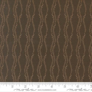 May include: A dark brown fabric featuring a repeating vertical pattern of light brown wavy vines with small leaves. The fabric is positioned above a white ruler with the text moda and modafabrics.com printed along the bottom edge.