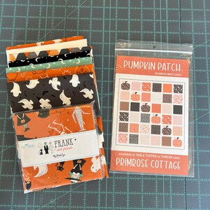 May include: A stack of Halloween-themed fabric squares with orange, black, and white patterns, including ghosts and pumpkins. A package of fabric squares is labeled "FRANK and friends". A pattern packet reads "PUMPKIN PATCH" and "PRIMROSE COTTAGE".