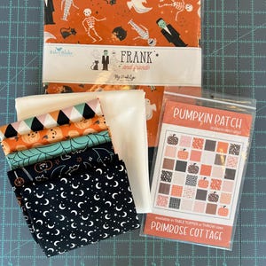 May include: A collection of Halloween-themed fabric bundles and a pattern. The fabric features orange backgrounds with ghosts, skeletons, and Frankenstein's monster. The pattern is for a pumpkin-themed quilt, with the text "Pumpkin Patch" and "Primrose Cottage".