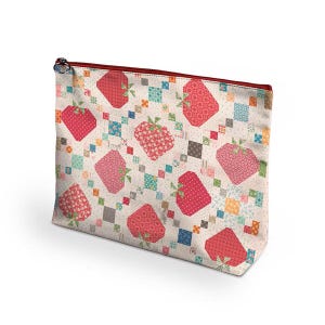May include: A zippered cosmetic bag with a repeating pattern of red strawberries and green stems on a cream background. The strawberries are surrounded by colorful patchwork squares. The zipper is red.