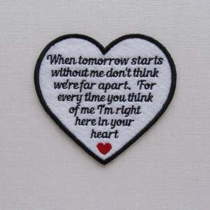May include: White heart-shaped patch with black embroidered text that reads "When tomorrow starts without me don't think we're far apart. For every time you think of me I'm right here in your heart". A small red heart is embroidered at the bottom of the patch.