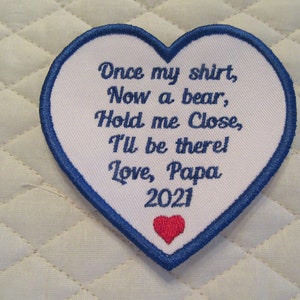 May include: White heart-shaped patch with blue edging and red heart in the bottom corner. The patch has embroidered text that reads "Once my shirt, Now a bear, Hold me Close, I'll be there! Love, Papa 2021".