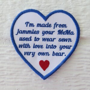May include: A blue heart-shaped patch with white fabric and blue stitching. The patch has red embroidered hearts and the text "I'm made from Jammles your MeMa used to wear sewn with love into your very own bear."