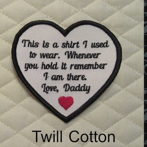 May include: White heart-shaped patch with black stitching and a red heart in the center. The patch has the text "This is a shirt I used to wear. Whenever you hold it remember I am there. Love, Daddy" embroidered in black.