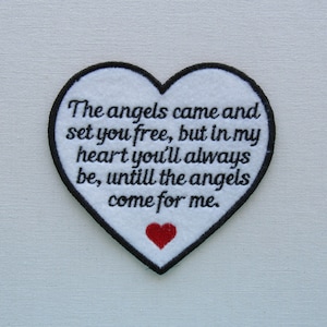May include: White heart-shaped patch with black stitching and a red heart in the center. The text on the patch reads: "The angels came and set you free, but in my heart you'll always be, until the angels come for me."