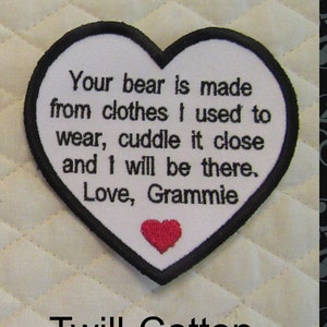 May include: White heart-shaped patch with black stitching and a red heart in the center. The patch says "Your bear is made from clothes I used to wear, cuddle it close and I will be there. Love, Grammie". The patch is made of twill cotton.