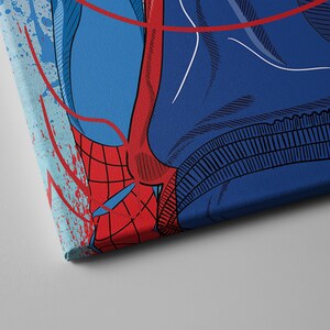 Op de afbeelding: Een close-up van een rood en blauw canvas print met een superheld met een webdesign. De print heeft een verweerd, gespat effect.