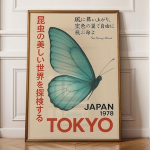 May include: A framed vintage poster featuring a teal butterfly with a detailed wing. The poster has Japanese text and the words "JAPAN 1978 TOKYO" in red. The background is a cream color, and the frame is brown.