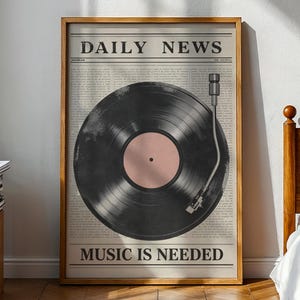 May include: A framed print featuring a vintage-style design. The artwork showcases a black vinyl record with a pink center, set against a newspaper background. The text "DAILY NEWS" and "MUSIC IS NEEDED" are displayed.