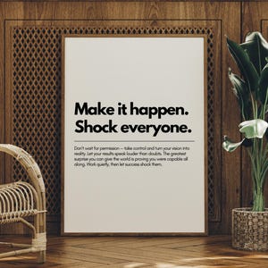 以下が含まれることがあります： 「Make it happen. Shock everyone.」というテキストが黒いフォントで書かれた額入りのプリント。プリントは木製の壁に飾られており、籐の椅子と鉢植えの植物が前景に配置されています。