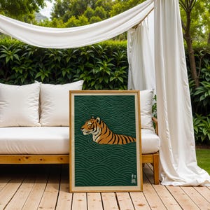 May include: A framed art print featuring a tiger swimming in water. The tiger is orange and black, set against a dark green background with a wave pattern. The frame is a light brown color.