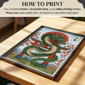 May include: Framed art print featuring a green dragon with red accents, a red sun, and a Japanese gate. The artwork includes cherry blossoms and the Japanese word for Japan. The frame is black.