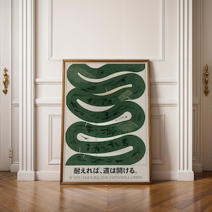 May include: A framed art print with a green, winding design and Japanese text. The artwork features a cream background with a stylized green snake-like shape and Japanese characters. The bottom of the print includes the English translation: "IF YOU ENDURE, THE PATH WILL OPEN."