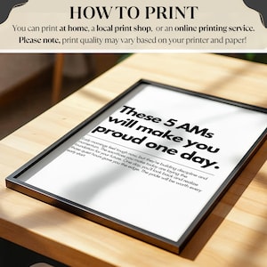 Pu&ograve; includere: Una stampa incorniciata con il testo "These 5 AMs will make you proud one day." La cornice nera circonda uno sfondo bianco con testo nero. La stampa &egrave; su una superficie di legno.
