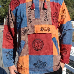 May include: A long-sleeved shirt with a hood, made in a patchwork style. The shirt is made of cotton and features a variety of colourful printed designs, including a sun, a flower, and the symbol Om.