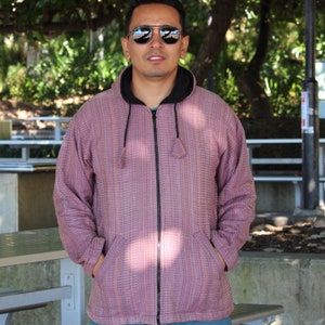 May include: A pink and white striped zip-up hoodie with a black zipper and hood. The hoodie has two pockets on the front.